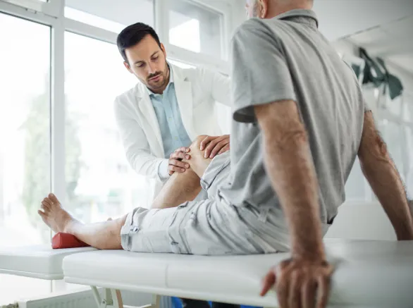 Senior man having his knee examined by a doctor.