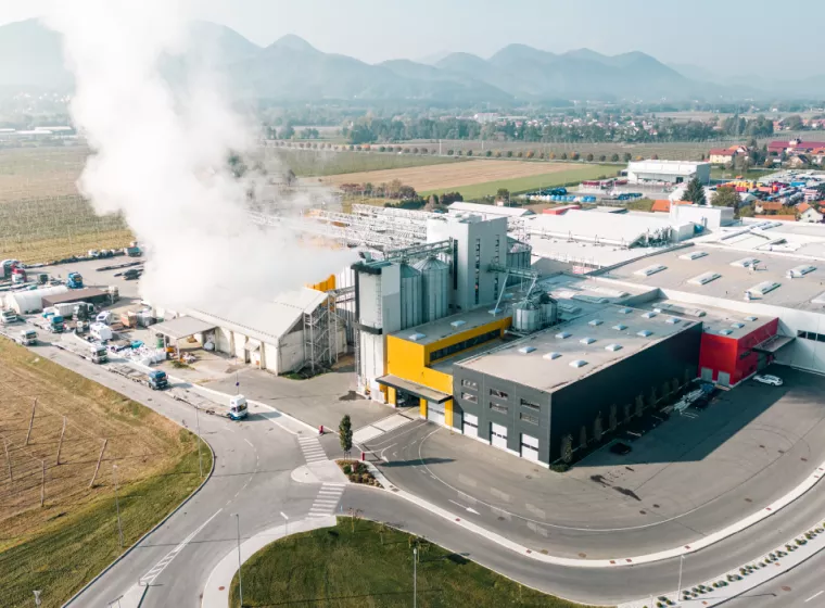 Aerial view of a manufacturing plant with smoke billowing from smokestacks