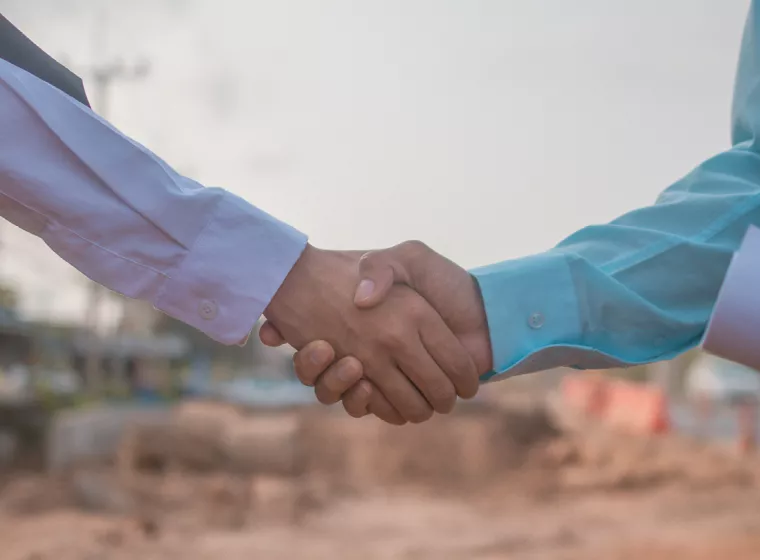 Businesspeople shaking hands in agreement. Exponent engineering expertise for construction disputes.