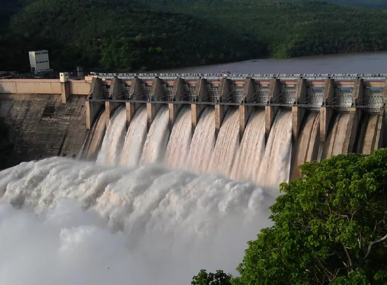 A large power generation dam, water rushing through open concrete gates on a river. Exponent utility and industrial power consulting.