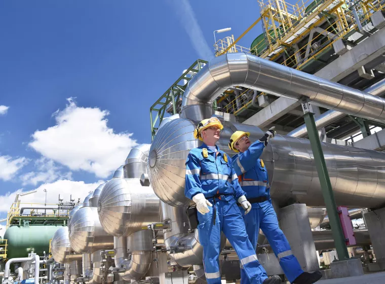 group of industrial workers in a refinery - oil processing equipment and machinery