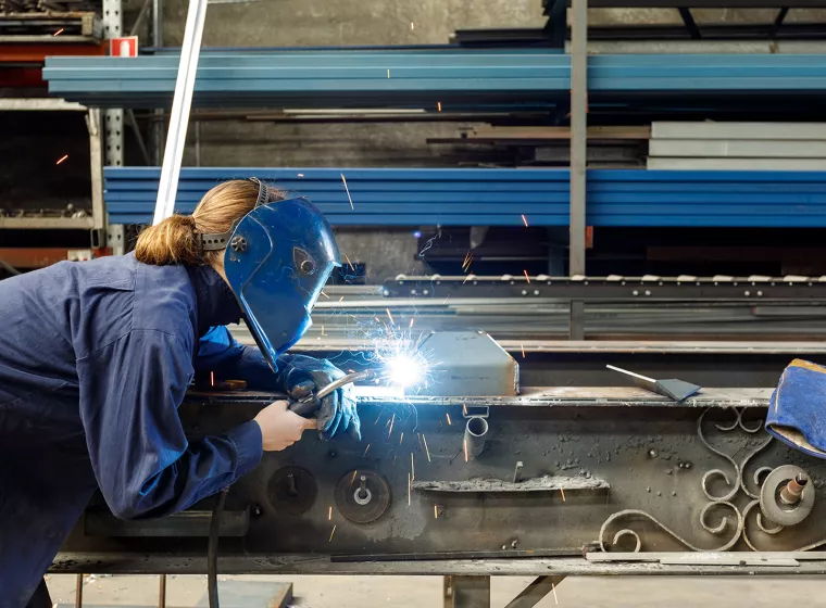 Welder working on steel beams. Exponent provides product process advisory for all types of materials.