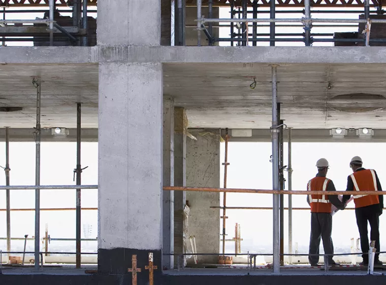 Two professionals on a buidling construction site. Exponent engineers consult on construction design defects.