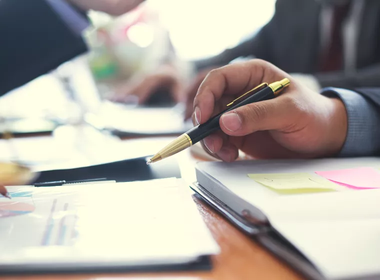 Stakeholders discuss important paperwork at a desk. Exponent provides technical consulting for disputes and claims. 