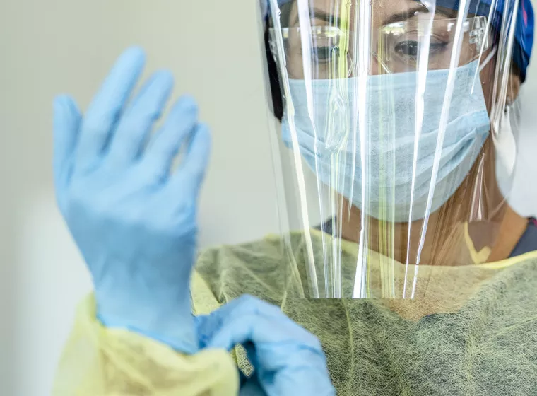 A healthcare worker wears personal protection gear. Exponent helps you improve workplace health and safety with health risk assessments.
