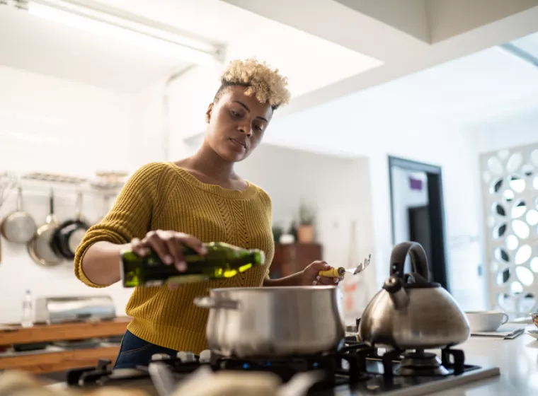 Person cooking on stove. Exponent helps manufacturers improve the safety and performance of all types of appliances and consumer products.