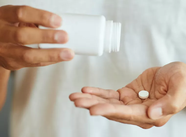 A person dispenses medicine from a bottle. Exponent helps improve the safety and efficacy of pharmaceutical products.
