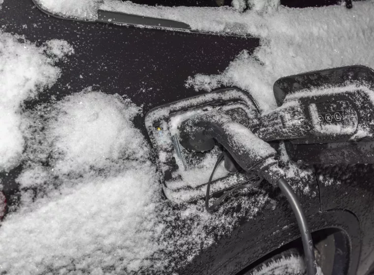 View of electric car with connected charging cable on frosty winter background