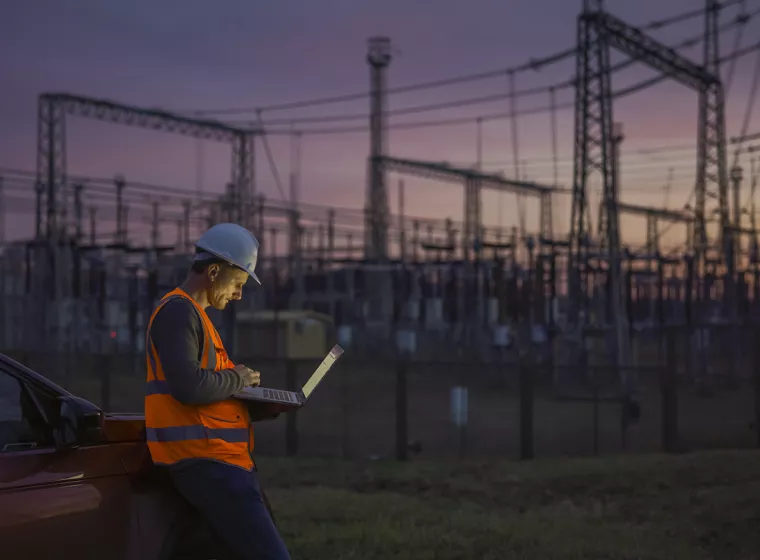 Electrical utility worker in the field, entering data into a tablet. Exponent's risk assessments improve efficiency and mitigate risks. 