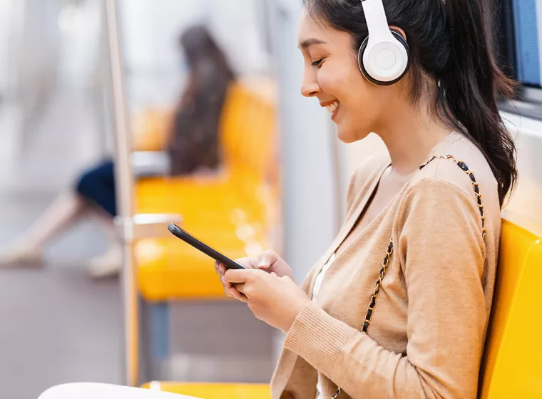 A person sitting in a train wearing headphones. Exponent helps manufacturers improve the quality and performance of consumer products.