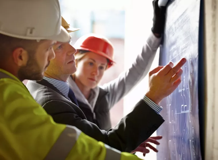 Workers at a construction site consult the building design blueprints. Exponent provides support for all types of construction projects.