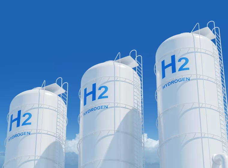 Large storage tanks with H2 and HYDROGEN labels on a blue sky background, representing hydrogen energy storage