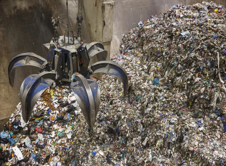 Mechanical claw hand grabbing pile of mixed waste