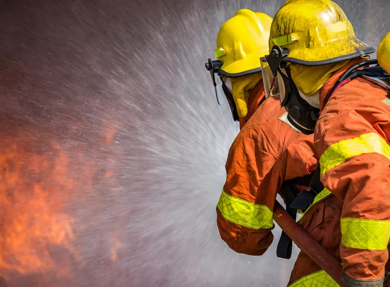 Firefighters work to extinguish flames. Exponent fire protection engineering helps create fire prevention strategies.
