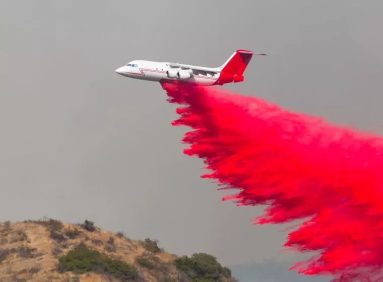 Pink fire retardant drops from a plane.