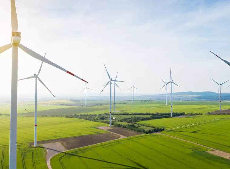 Multiple wind turbines blowing in the wind in a flat, green valley