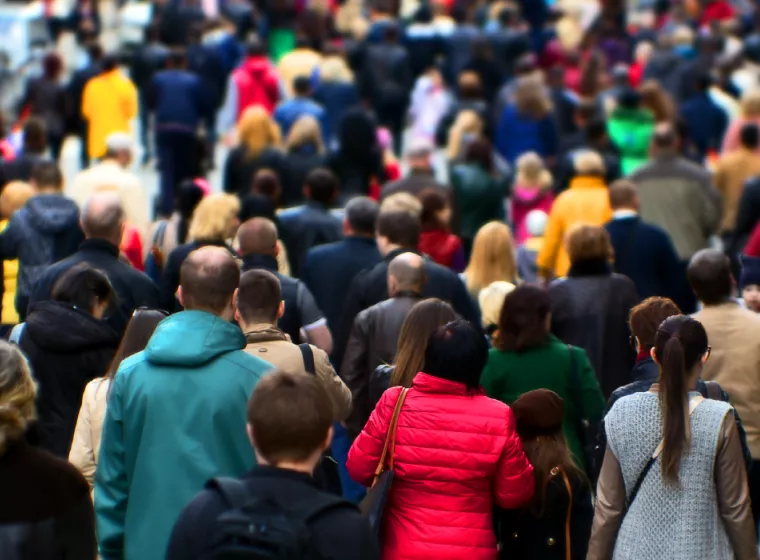 Crowd of people wearing coats and walking on sidewalk. Exponent conducts epidemiological and  biostatistical research.