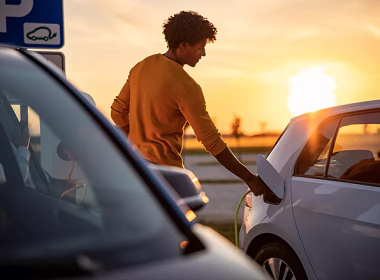 Person charging an electric car. Exponent's research, testing and safety evaluations improve automotive innovations.