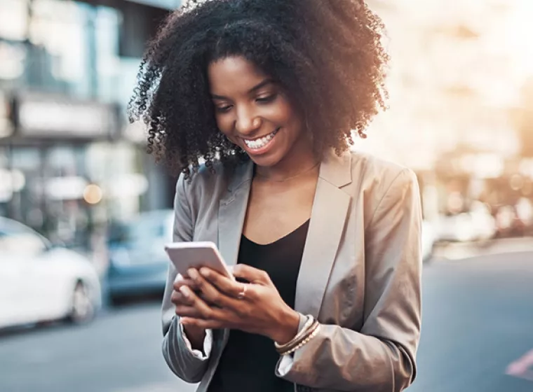 Person smiling and texting on cell phone. Exponent's technical research helps innovate smarter and better performing phones and electronics