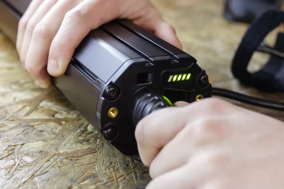 Close up shoto of male hands plugging in charger to an electric bicycle battery