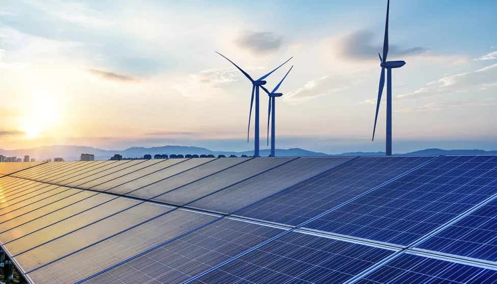 A view of solar panels and windmills at sunset