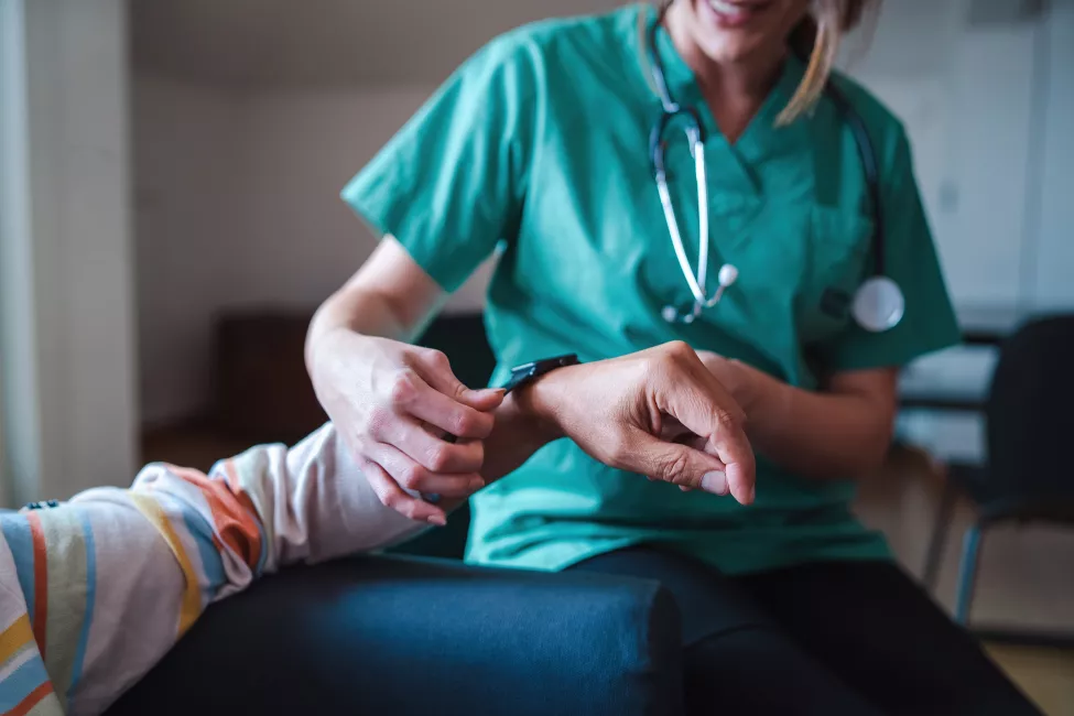 A woman from the medical health system wears a smartwatch for remote monitoring of vital signs on an elderly person