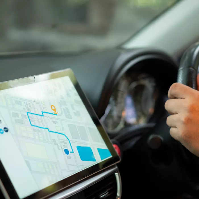 Hands on steering wheel driving on right side of car guided by GPS system