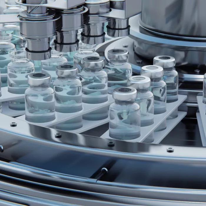 Vaccine manufacturing, machine puts caps on bottles vials passing on conveyor belt.