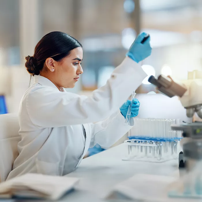 scientist in a laboratory using a pipette to examine a sample with a microscope