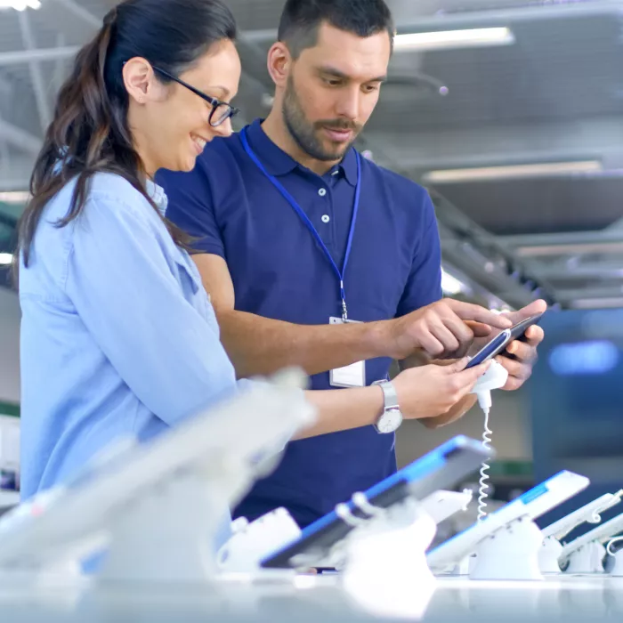 Customer and salesperson look at a electronic device at a store together.