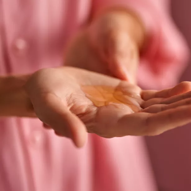 Close up of a hand with orange serum pooling in the middle of the palm