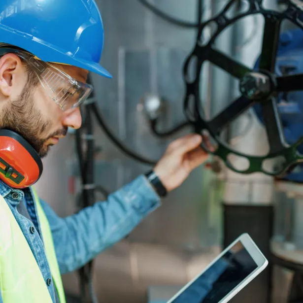 Person inspecting Oil and Gas Infrastructure while review notes on a tablet