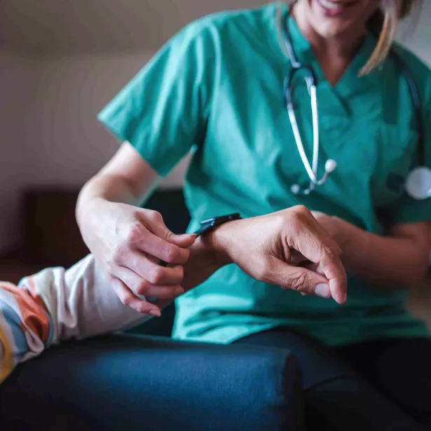 Medical professional wearing scrubs and stethoscope takes care of patient