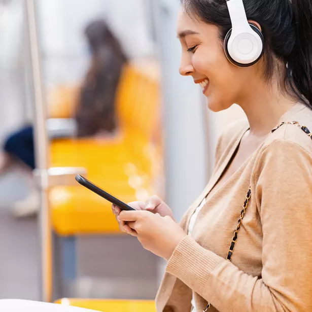 A person sitting in a train wearing headphones. Exponent helps manufacturers improve the quality and performance of consumer products.