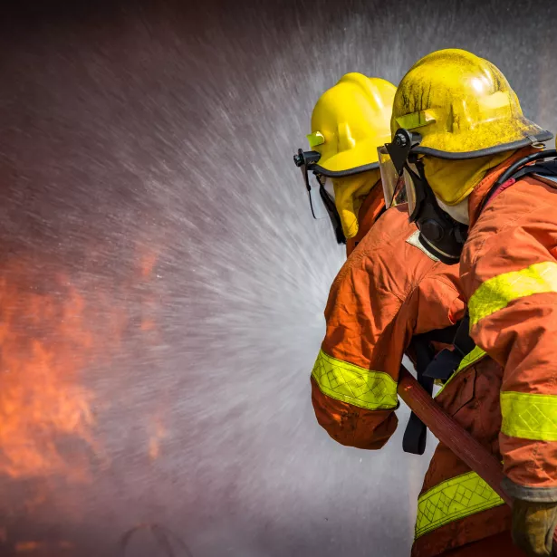 2 firefighters spraying high pressure water to fire