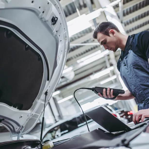 mechanic in uniform is working in auto service. Car repair and maintenance. Performing engine diagnostics