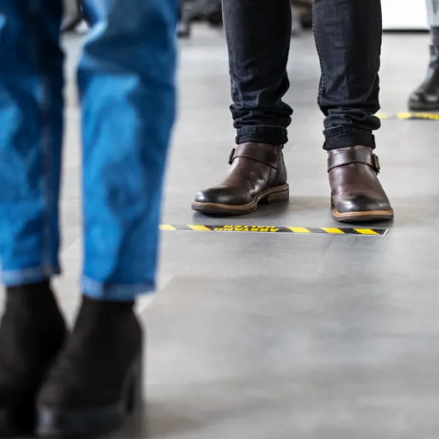 People standing on floor markers to social distance while waiting in line