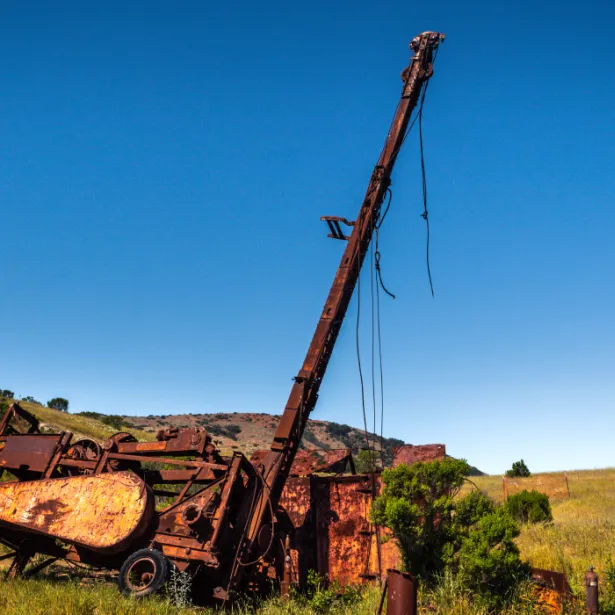 Rusty abandoned well and equipment in the middle of a hillside field