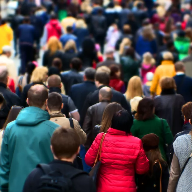 Crowd of people wearing coats and walking on sidewalk. Exponent conducts epidemiological and  biostatistical research.