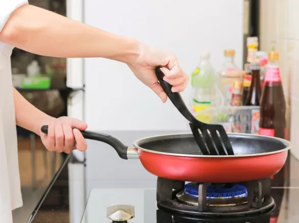 Cropped Hands Of Woman Frying Food In Kitchen