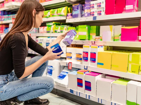 Young woman crouching and choosing panty liners sanitary pads
