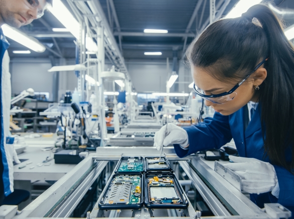 Electronics Factory Workers Assembling Circuit Boards by Hand While it Stands on the Assembly Line