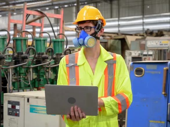 Caucasian male with protective mask with laptop working in factory area