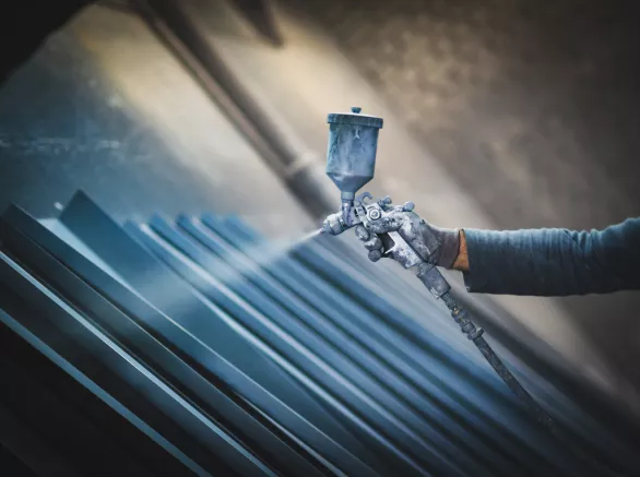 Man painting metal products with a spray gun
