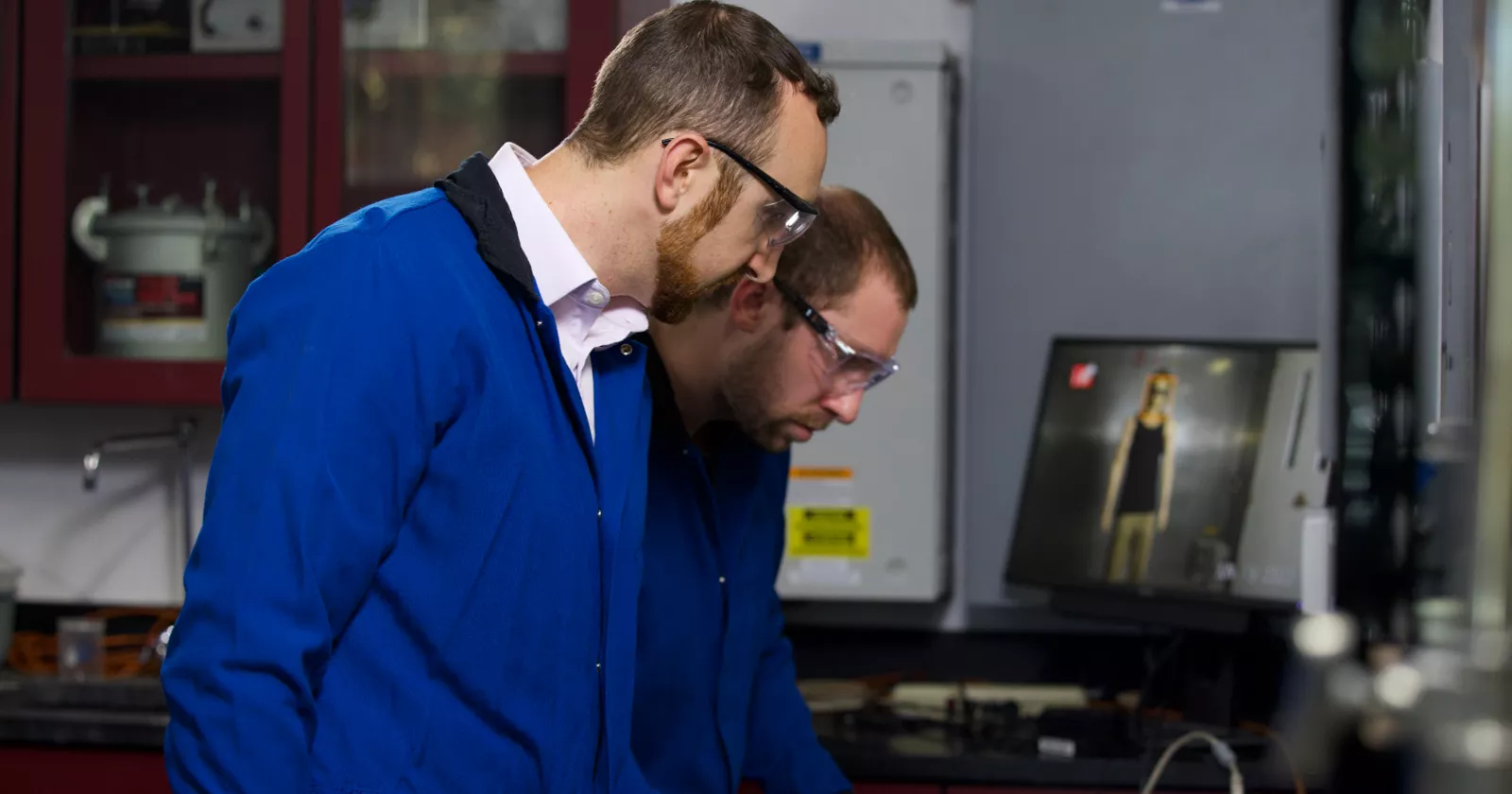 Two engineers in safety glasses engaged in a battery performance test. Exponent engineers assist with battery safety and recall support