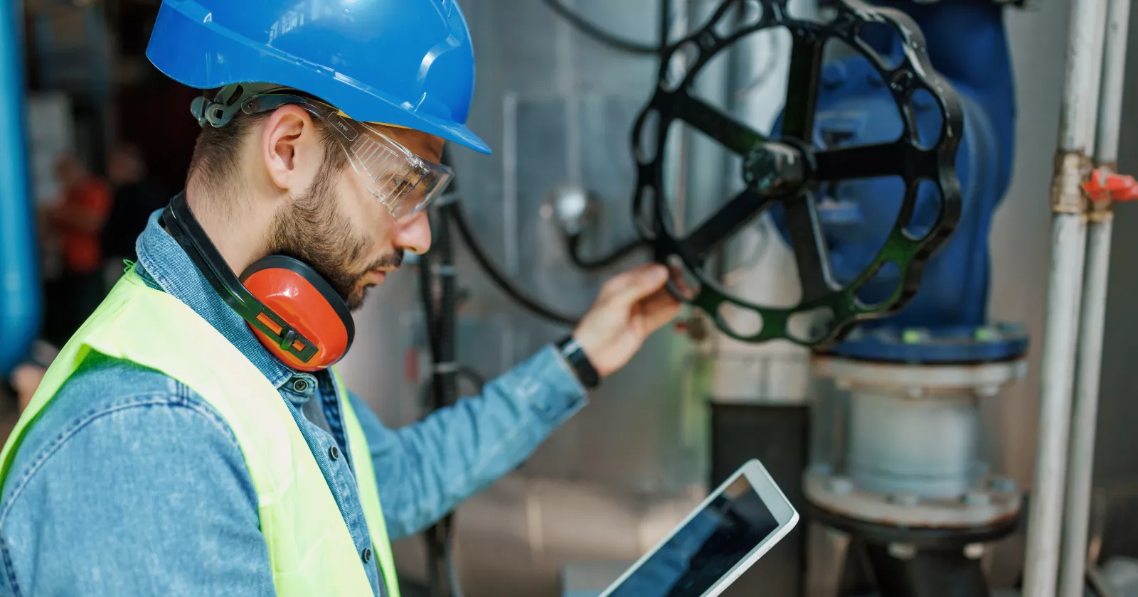 Person inspecting Oil and Gas Infrastructure while review notes on a tablet