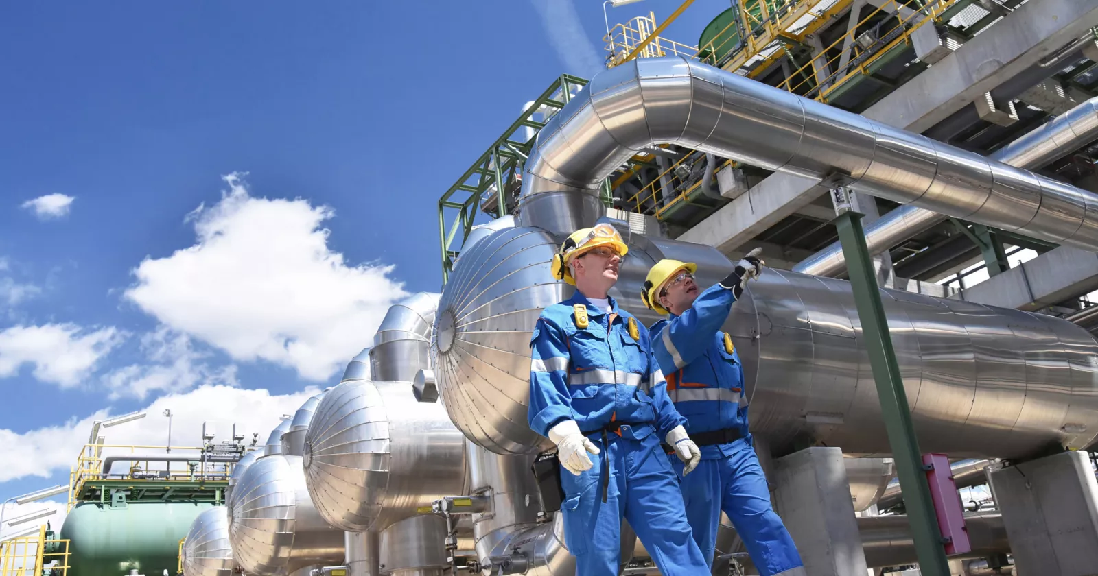 group of industrial workers in a refinery - oil processing equipment and machinery