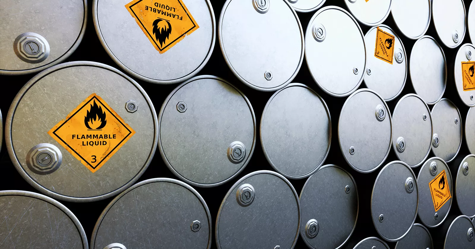 Stacks of steel barrels labeled with flammable liquid warning signs. Exponent helps improve safety of hazardous chemicals.