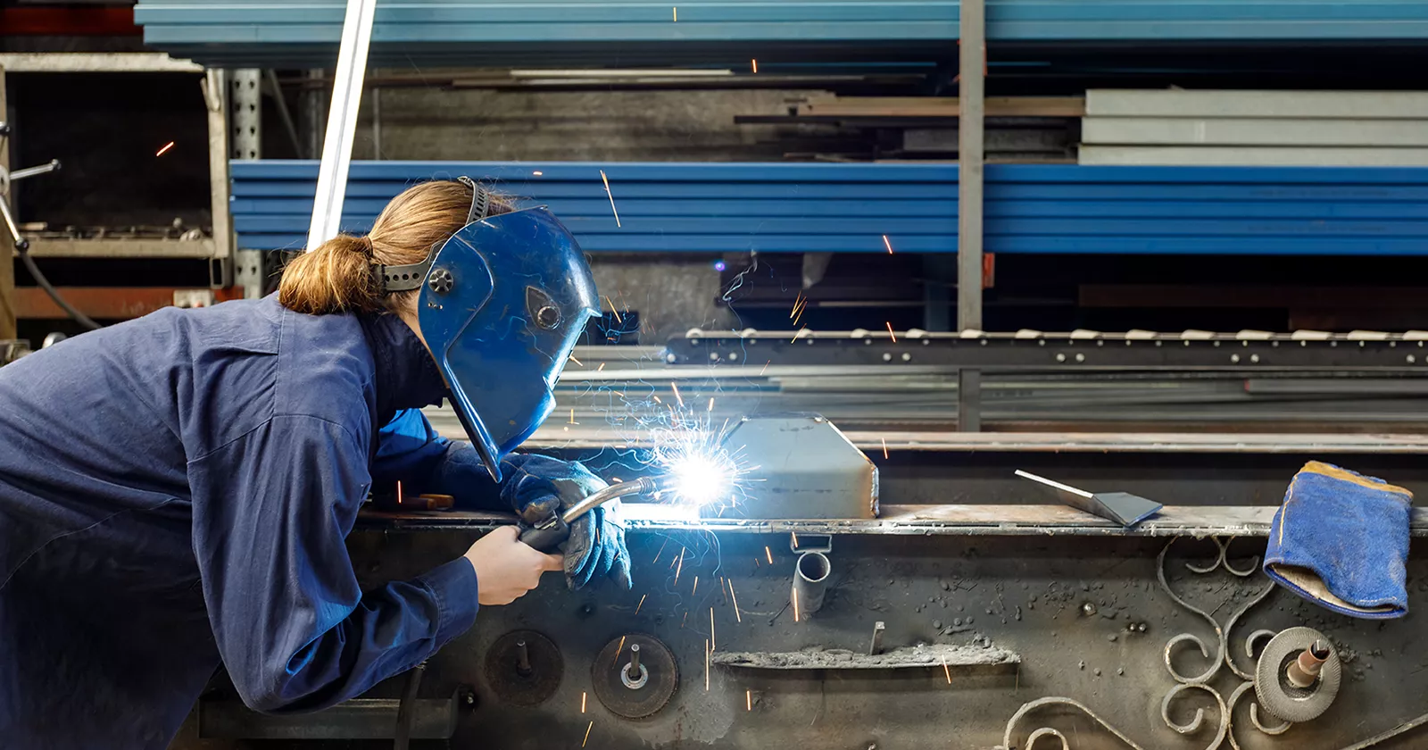 Welder working on steel beams. Exponent provides product process advisory for all types of materials.