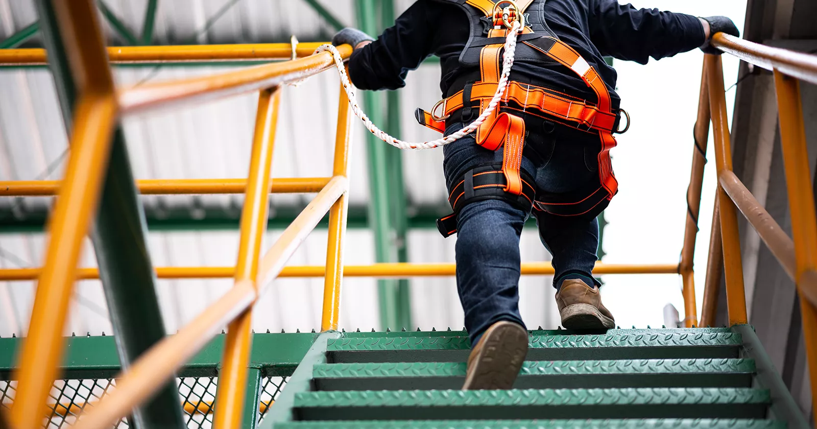 Worker in bright color safety gear running up steps. Exponent conducts construction risk analyses.